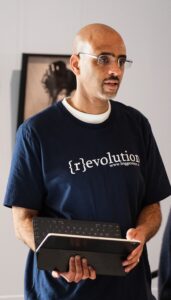 Steven Ward, wearing glasses and a t-shirt that says "revolution."